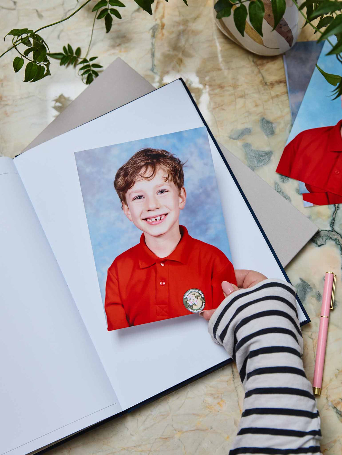 A school photo with a plant and pink pen and school journal