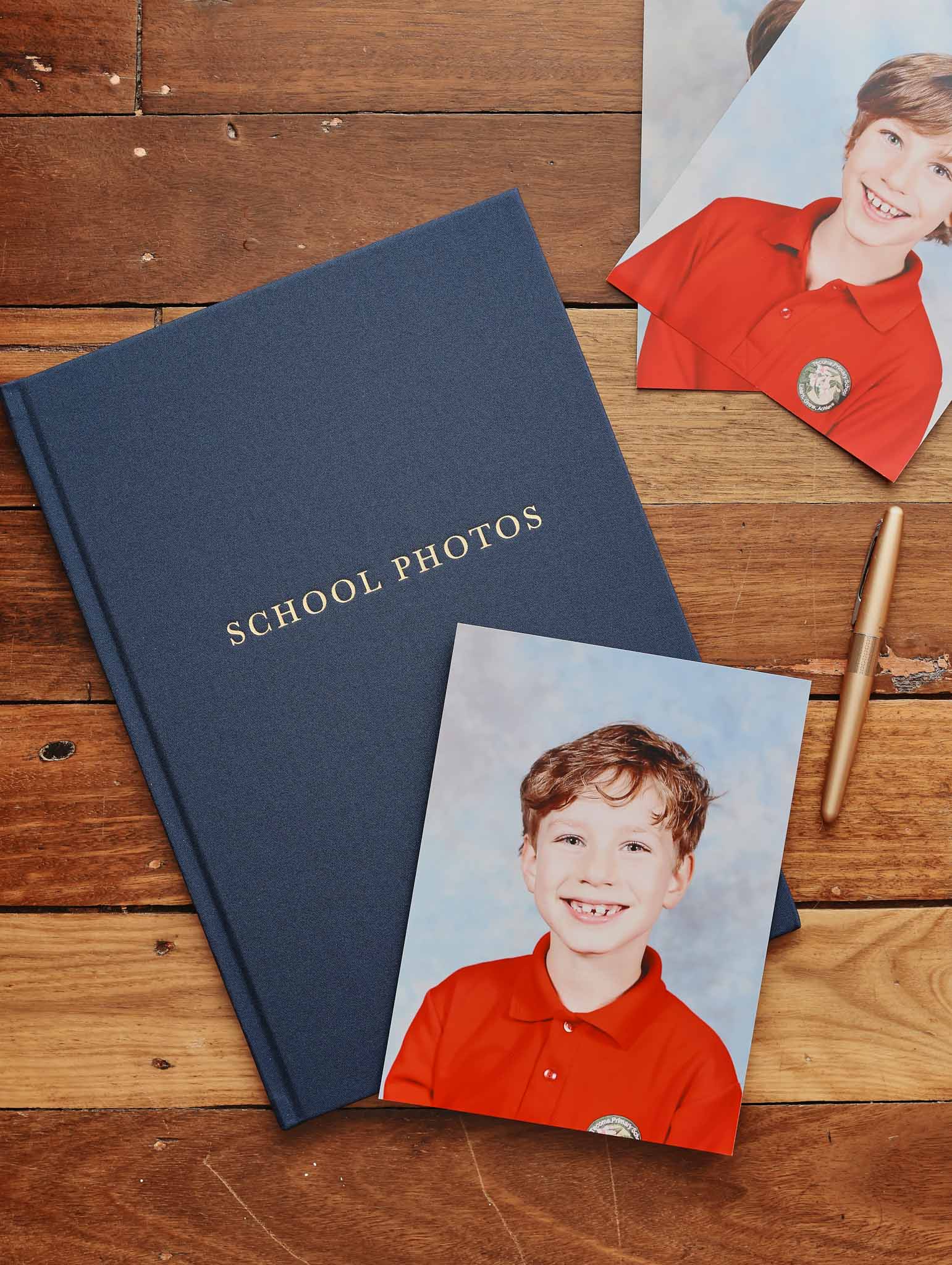 Navy album labeled 'School Photos' with a school portrait photo on a wooden surface.