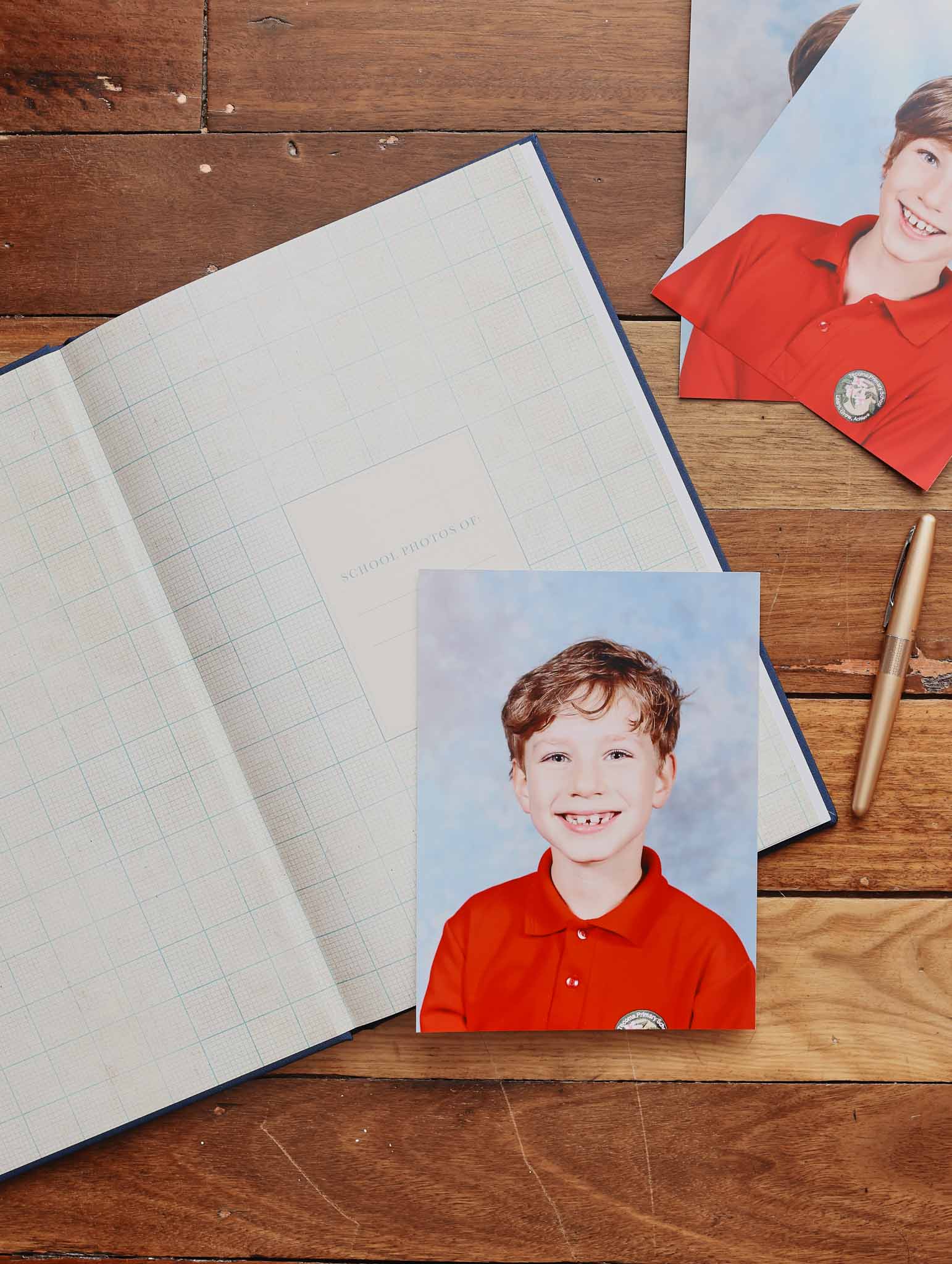 Navy album labeled 'School Photos' with a school portrait photo on a wooden surface.
